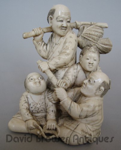 Japanese ivory okimono of men and children, with one wearing a mask